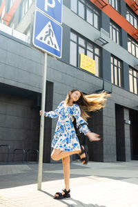 Portrait of young woman standing against building