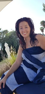 Portrait of smiling woman sitting against sky