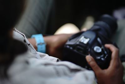 Close-up of hand holding camera on safari with blue watch