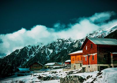 Houses by snow covered mountains against sky