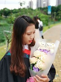 Close-up of a beautiful woman holding red flowering plants