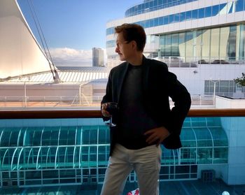 Man having wine while standing against buildings in city