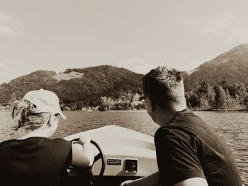 Rear view of man and woman on lake against mountains