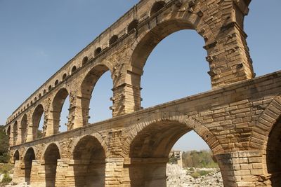 Low angle view of aqueduct against clear blue sky
