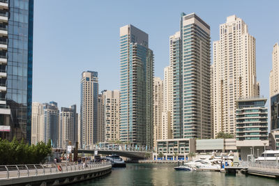 Modern buildings by river against sky in city