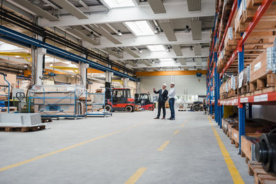 Two men wearing hard hats talking in factory shop floor