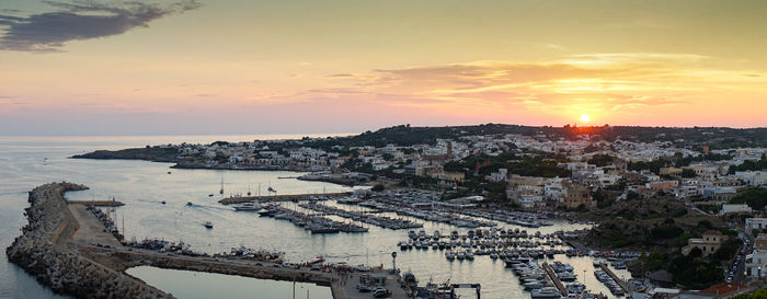 High angle view of sea and buildings against sky during sunset