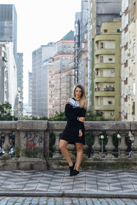 Portrait of woman standing against buildings in city