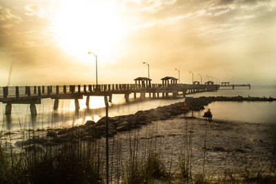 Pier over sea against sky during sunset