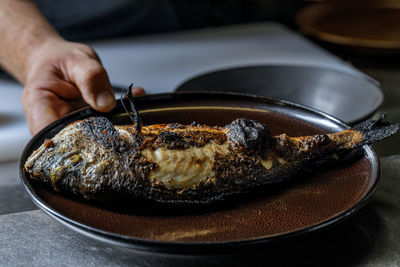 Cropped hand of person preparing food in plate on table