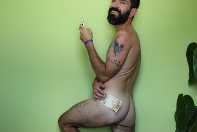 Young man smoking cigarette against green background