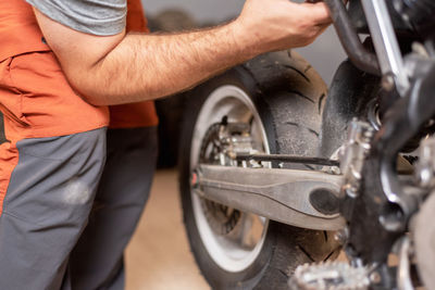 Midsection of mechanic repairing motorcycle in garage