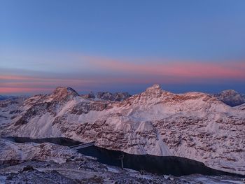 Scenic view of snow covered mountains against sky at sunset