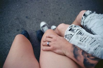 Low section of couple sitting on road