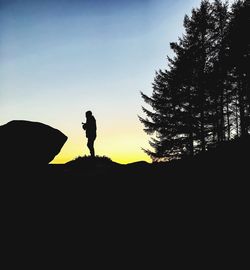 Silhouette man standing by trees against sky during sunset