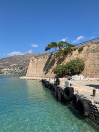 View of castle by sea against blue sky