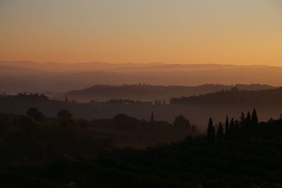 Silhouette trees on landscape against sky during sunset