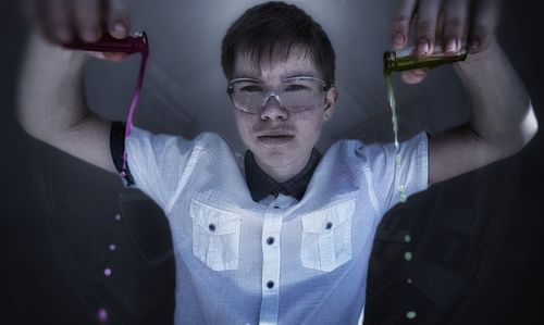 Portrait of young man poring chemicals at laboratory