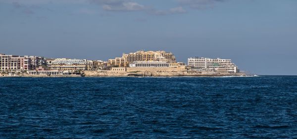 Sea by buildings against sky in city