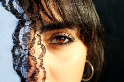 Close-up portrait of woman wearing mascara by textile in sunny day