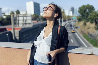 Young woman looking away while standing outdoors