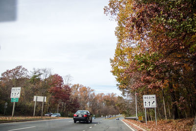 Road amidst trees against sky during autumn