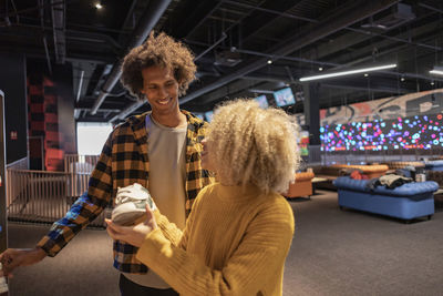 Girl with friend holding bowling shoes