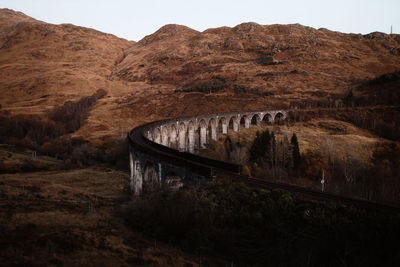 Arch bridge over mountains against sky