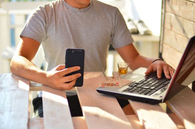 Midsection of man using technologies at table in cafe