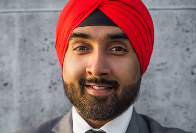 Close-up portrait of businessman wearing turban standing against wall