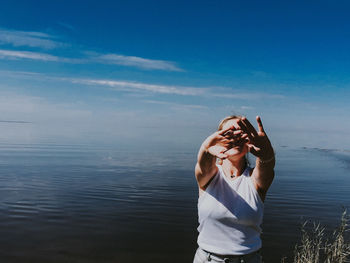 Woman photographing sea against sky
