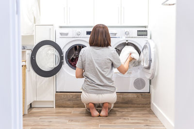 Rear view of woman removing clothes from washing machine