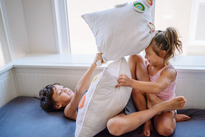 Brother and sister playing at home pillow fight