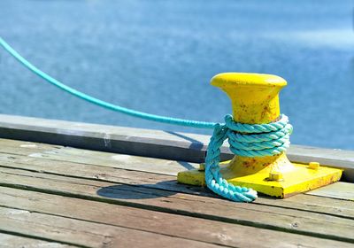 Close-up of yellow rope tied to wooden jetty