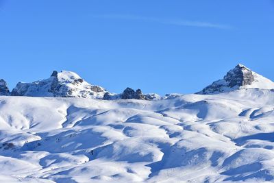 Scenic view of snowcapped mountains against clear blue sky