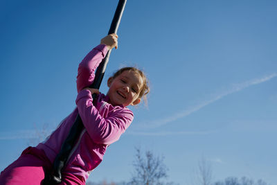 Low angle view of girl playing against sky