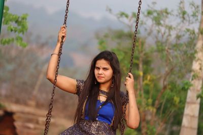 Portrait of young woman with swing in park