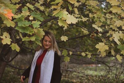 Portrait of young woman standing by tree