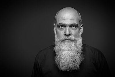 Portrait of bearded man against black background