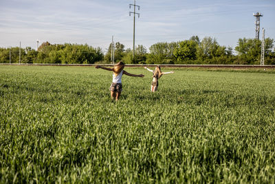 Friends enjoying on grassy field against sky