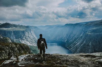 Rear view of man standing on rock against mountains