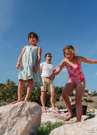 Full length of siblings standing on rock