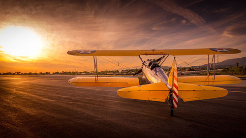 Airplane on beach against sky during sunset