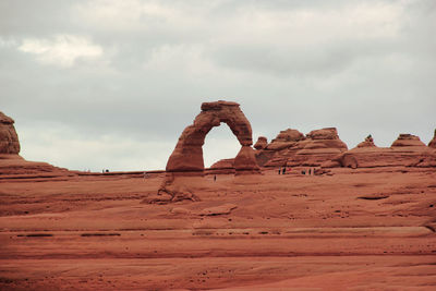 Rock formations in desert against cloudy sky