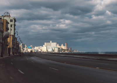 Road by buildings against sky in city