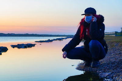 Man photographing at beach against sky during sunset