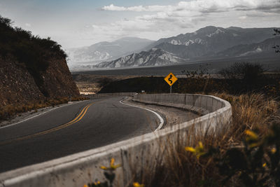 Road by mountains against sky