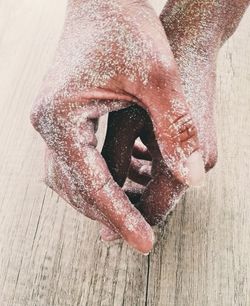 Close-up of cropped hands with sands on floorboard