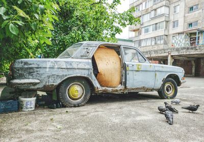 Abandoned car on street against building