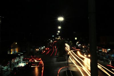 Illuminated city street against sky at night